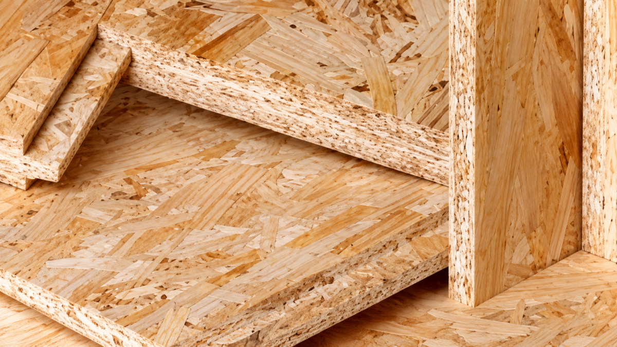 Nahaufnahme mehrerer übereinanderliegender und aufrecht stehender OSB-Platten. Die groben, verpressten Holzspäne bilden eine markante Oberfläche in hellen Beige- und Brauntönen. An den Schnittkanten ist der verdichtete Aufbau der Platten sichtbar.